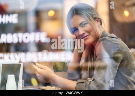 Young businesswoman in a cafe, seen through window Stock Photo