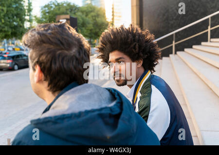 Two casual businessmen sitting on stairs having a break Stock Photo