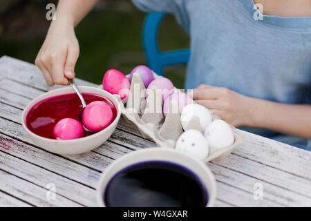 Close-up of girl dyeing Easter eggs in garden Stock Photo