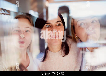 Mother and daughters pressing noses against window pane Stock Photo