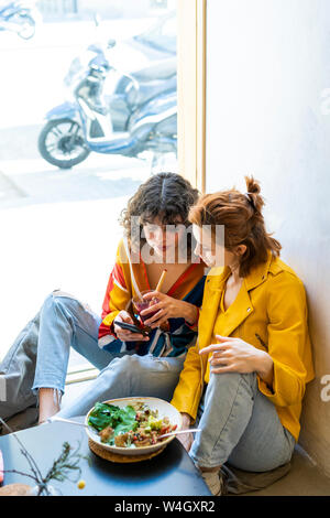 Two young women in a cafe looking at cell phone Stock Photo