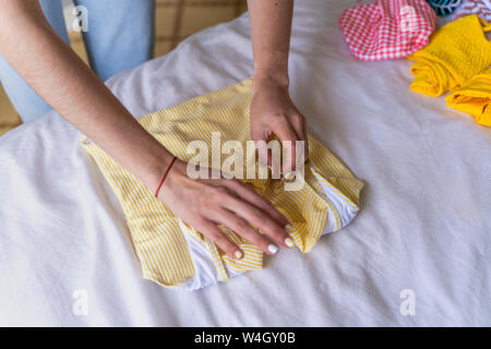 Close-up of woman folding clothes on bed