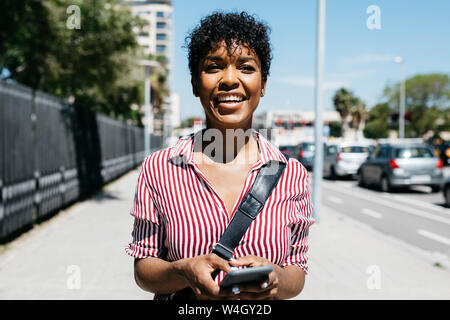 Woman using smartphone while walking in the city Stock Photo