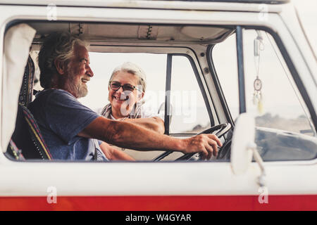 Senior couple traveling in a vintage van, taking a break at the sea, talking Stock Photo