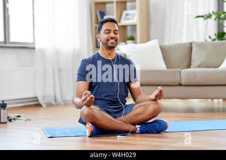 indian man meditating in lotus pose at home Stock Photo