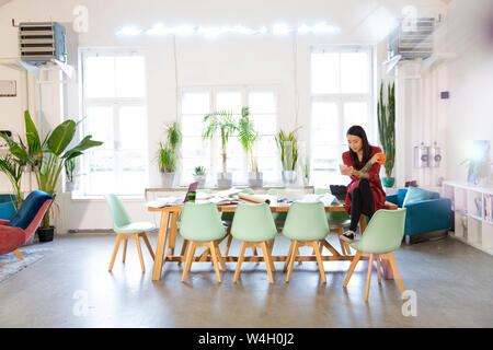 Woman using cell phone in modern office Stock Photo