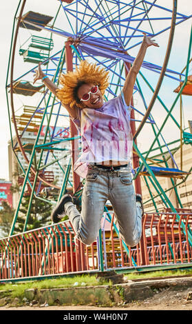 Happy woman jumping in front of a Ferris wheel Stock Photo