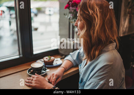 Young woman sitting at the window in a cafe Stock Photo