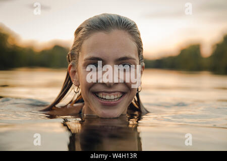 Young woman swimming in lake at sunset Stock Photo