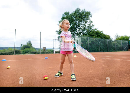 Little girl, lerning to play tennis Stock Photo