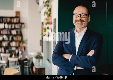 Portrait of happy mature businessman standing in a cafe Stock Photo