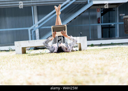 Female ballet dancer in front of an office using laptop lying Stock Photo