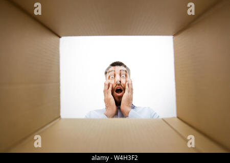 shocked man looking into open parcel box Stock Photo