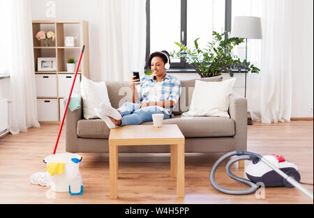 woman in headphones resting after home cleaning Stock Photo