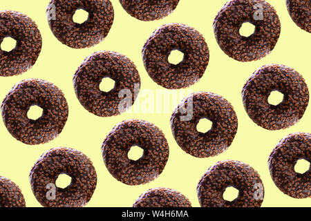 Chocolate donuts on a yellow background. Cheerful, festive background and seamless texture. Stock Photo