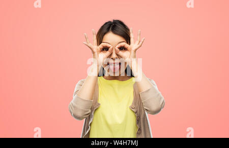 smiling asian woman looking through finger glasses Stock Photo