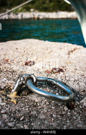 Crazy crafted silver metal mooring ring nailed in the concrete on the shore Stock Photo