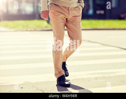 senior man walking along city crosswalk Stock Photo