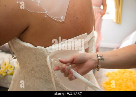 Wedding dress being done up on a Brides wedding day, close up of wedding dress being done up before the ceremony Stock Photo