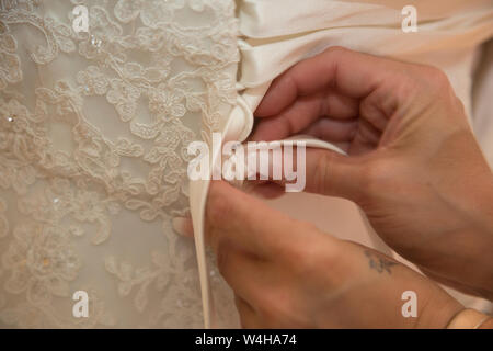 Wedding dress being done up on a Brides wedding day, close up of wedding dress being done up before the ceremony Stock Photo