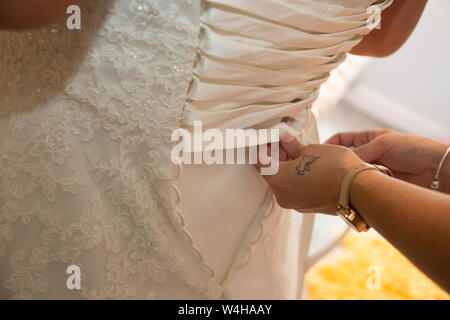 Wedding dress being done up on a Brides wedding day, close up of wedding dress being done up before the ceremony Stock Photo