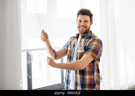 man opening roller blind on window at home Stock Photo