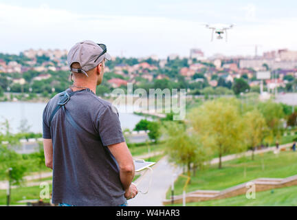 Young Man watching and navigating a flying drone. Stock Photo