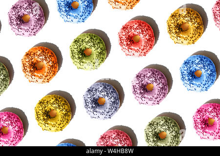 Repeating food pattern top view on multi-colored donuts on a white isolated background. Colors from the fashionable trendy palette of the season 2019. Stock Photo