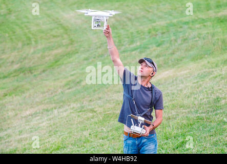 Young Man watching and navigating a flying drone. Stock Photo