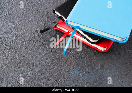 Stack of colorful notebooks for writing or books on dark background. Stock Photo