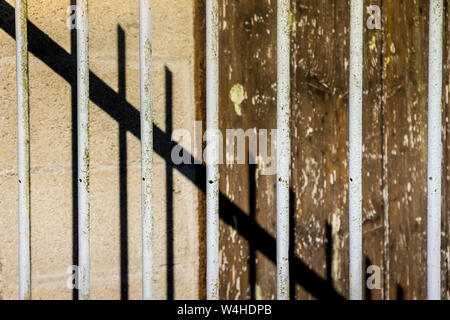 Old painted railings and corrugated wall with abstract shadows. Stock Photo