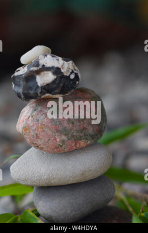 Stones balancing on each other. Around the leaves of bamboo. Balanced stones. SPA wellness. Stock Photo