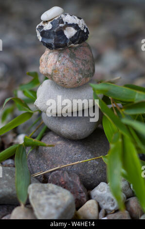 Stones balancing on each other. Around the leaves of bamboo. Balanced stones. SPA wellness. Stock Photo