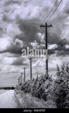 Electrical power poles and wires along rural Texas highway under dramatic skies in black and white Stock Photo