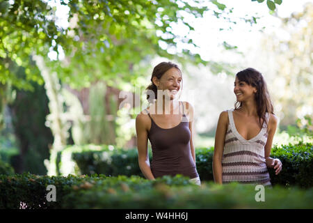 Two women friends taking a walk through the woods with a dog on a snowy ...