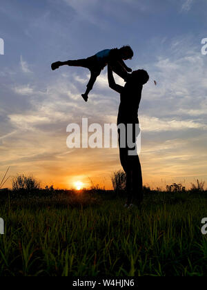 Silhouette Father Carrying Son Against Sky During Sunset. Stock Photo