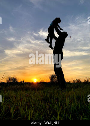 Silhouette Father Carrying Son Against Sky During Sunset. Stock Photo