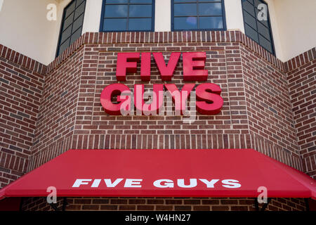 Maple Grove, Minnesota - July 21, 2019:  Exterior of a Five Guys fast food restaraunt, close up of the sign logo. This chain specializes in burgers an Stock Photo