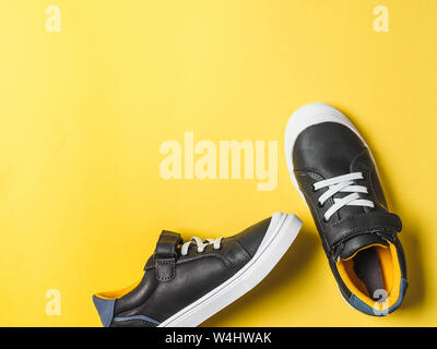 pair of new kids or adult sneakers on yellow background, top view. Flat lay gray and yellow or mustard color sneakers shoes on colorful bright background with copy space for text or design Stock Photo