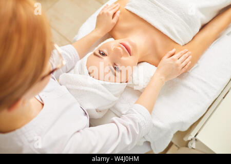 Beautiful woman lying on a table cosmetologist in the beauty salon. Stock Photo