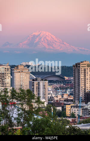 The Seattle Skyline from Kerry Park with reflections of the orange and pink sunset in the glass of the skyscrapers with Mount Rainier in the distance Stock Photo