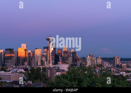 The Seattle Skyline from Kerry Park with reflections of the orange and pink sunset in the glass of the skyscrapers with Mount Rainier in the distance