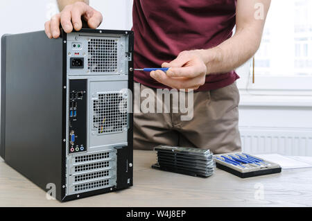 A man is unwinding the screw for access inside the desktop. Stock Photo