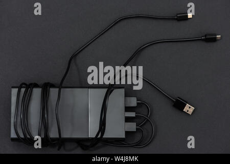The power bank with charging cables on a dark background. Stock Photo