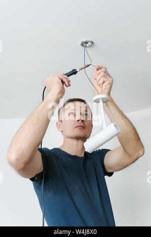 Installing a spotlight in the room. The man is a soldering wire. Stock Photo