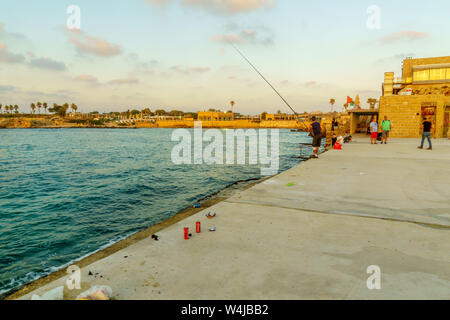 Caesarea, Israel - July 22, 2019: Sunset view of the old port, with fishermen and other visitors, in Caesarea National Park, Northern Israel Stock Photo