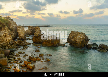 Caesarea, Israel - July 22, 2019: Sunset view of the old port, with fishermen and other visitors, in Caesarea National Park, Northern Israel Stock Photo