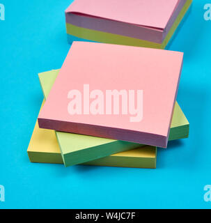 multicolored empty paper square stickers on blue background, close up Stock Photo