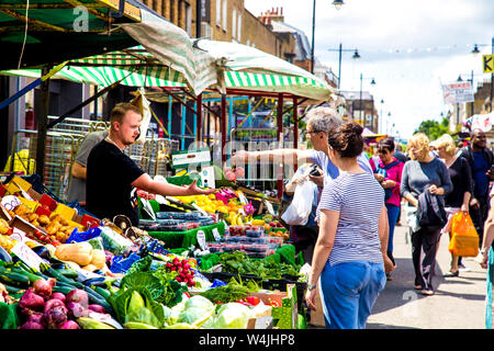 Green grocer stall with fruit and vegetables, people shopping at market, Chapel Market, Angel, London, UK Stock Photo