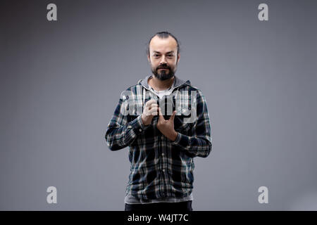 Relaxed friendly attractive bearded man in casual plaid shirt posing over grey with copy space smiling at the camera Stock Photo